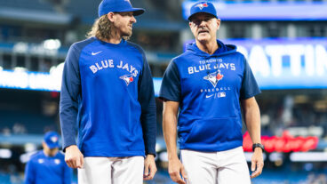 Kevin Gausman #34 of the Toronto Blue Jays walks to the dugout with pitching coach Pete Walker before playing the Boston Red Sox in their MLB game at the Rogers Centre.