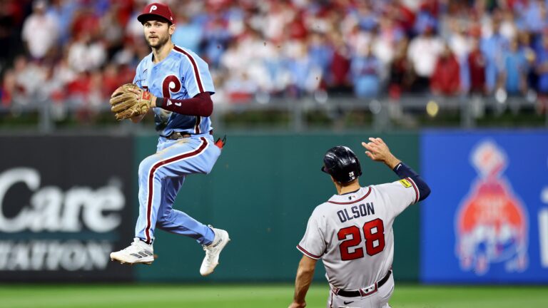 Trea Turner of the Philadelphia Phillies turns a double play past Matt Olson of the Atlanta Braves in the fourth inning during Game Four of the Division Series at Citizens Bank Park.