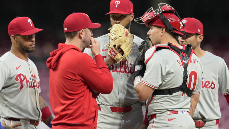 Cristopher Sánchez of the Philadelphia Phillies speaks with teammates at the pitcher's mound during the third inning of a baseball game against the Cincinnati Reds at Great American Ball Park.