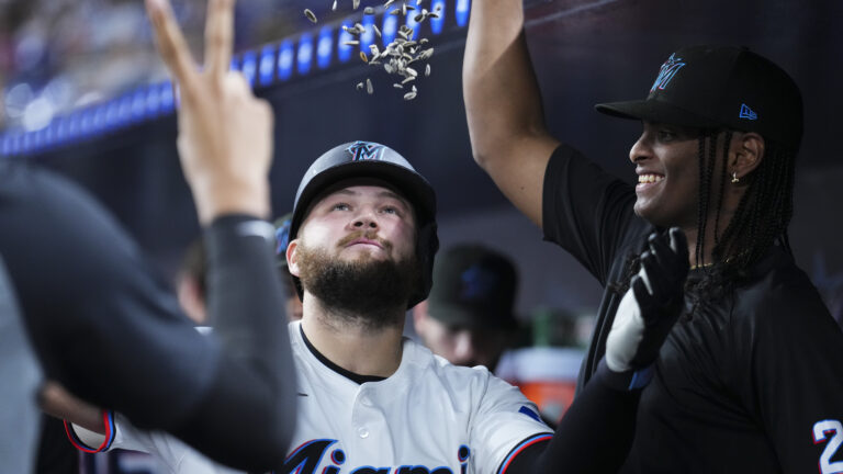 Jake Burger of the Miami Marlins celebrates with teammates in the dugout after hitting a home run against the Cincinnati Reds during the fifth inning at loanDepot park.