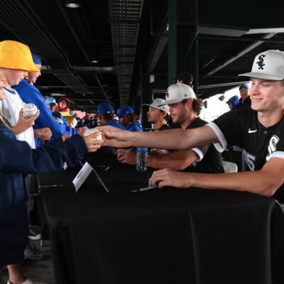 Top prospect Noah Schultz, a key piece of the Chicago White Sox rebuild, signs a baseball for a young fan during a rain delay prior to the game between the Chicago White Sox and the Chicago Cubs.
