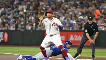 PHOENIX, ARIZONA - MARCH 27: Seiya Suzuki #27 of the Chicago Cubs slides safely into first base behind Josh Naylor #22 of the Arizona Diamondbacks in the second inning on Opening Day at Chase Field on March 27, 2025 in Phoenix, Arizona. (Photo by Norm Hall/Getty Images)