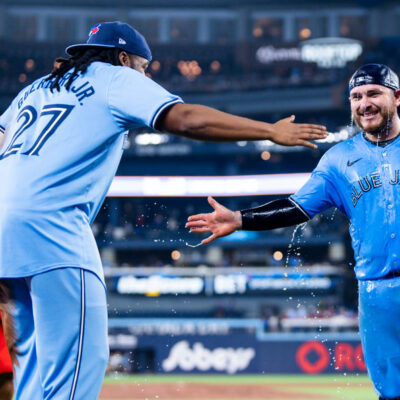 TORONTO, ON - APRIL 28: Alejandro Kirk #30 of the Toronto Blue Jays slap hands after getting doused in water by teammate Vladimir Guerrero Jr. #27 after their team defeated the Los Angeles Dodgers in their MLB game at the Rogers Centre on April 28, 2024 in Toronto, Ontario, Canada. (Photo by Mark Blinch/Getty Images)