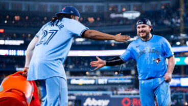 Alejandro Kirk #30 of the Toronto Blue Jays slap hands after getting doused in water by teammate Vladimir Guerrero Jr. #27