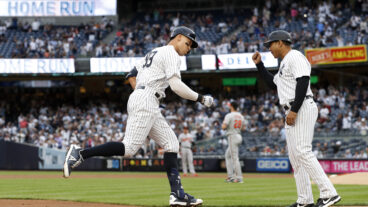 Aaron Judge of the New York Yankees celebrates his home run during the first inning against the Baltimore Orioles with third base coach Luis Rojas at Yankee Stadium.