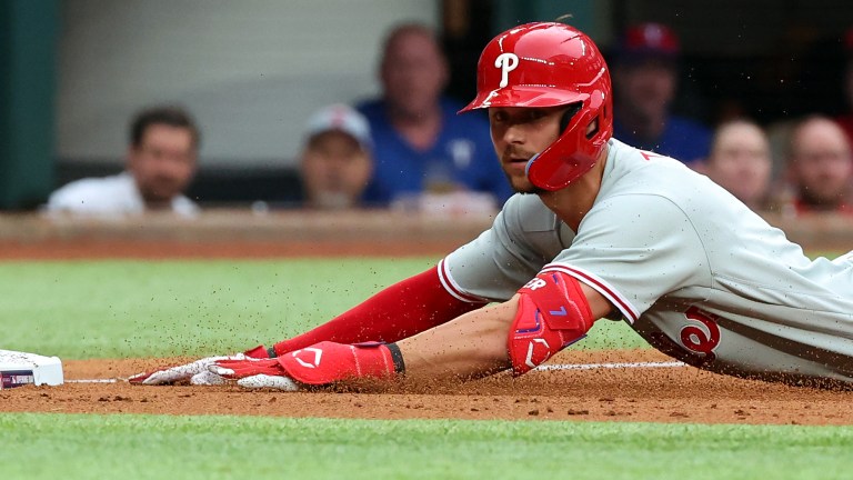 Trea Turner of the Philadelphia Phillies slides into third base on a triple in the third inning against the Texas Rangers on Opening Day at Globe Life Field.