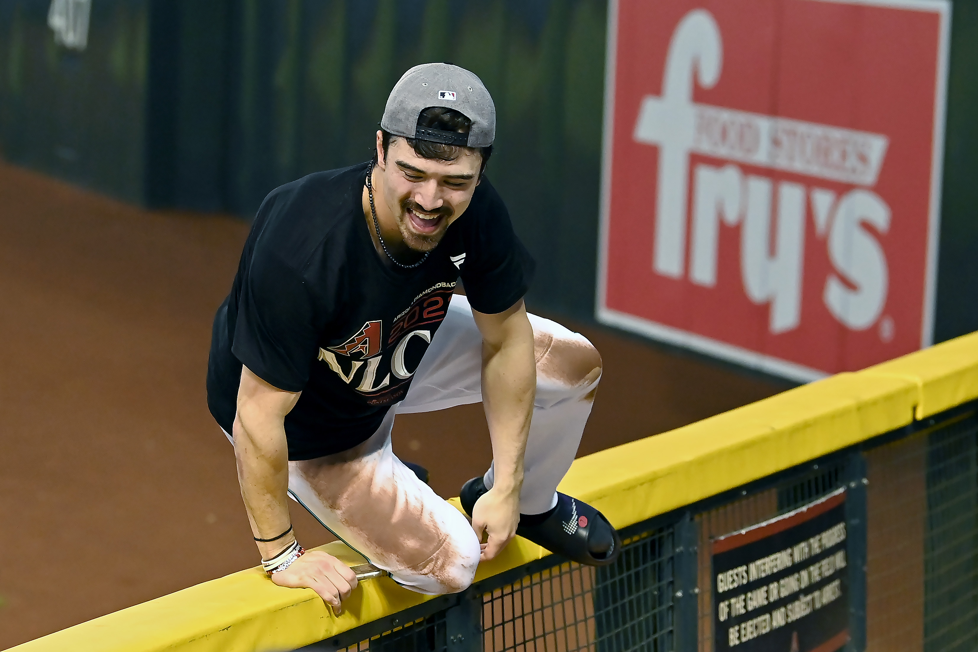 orbin Carroll #7 of the Arizona Diamondbacks climbs the outfield fence after beating the Los Angeles Dodgers 4-2 in Game Three of the Division Series at Chase Field.