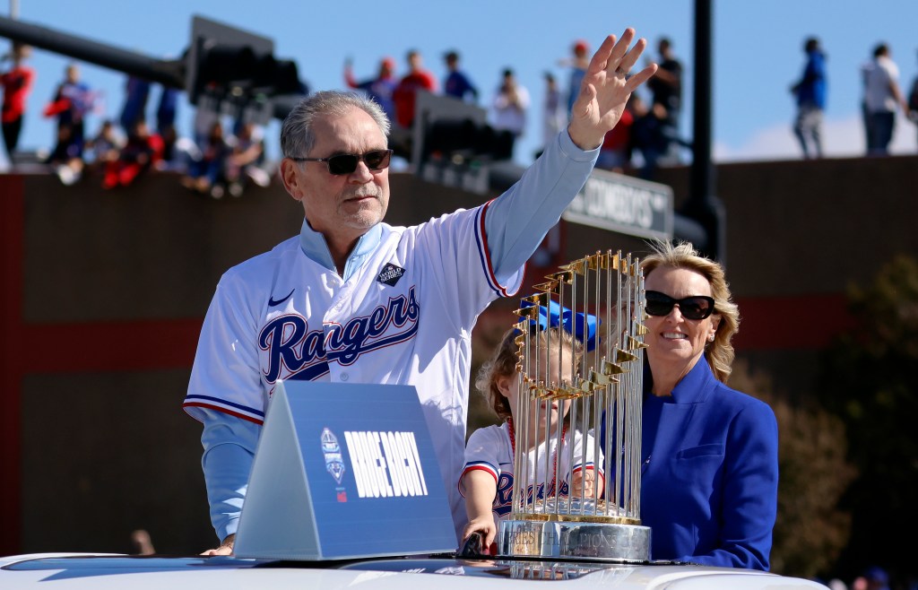 Texas Rangers manager Bruce Bochy and his wife Kim Seib ridie with the World Series trophy and wave to fans lining the street and buildings during the World Series Victory Parade outside Globe Life Field on November 3, 2023 in Arlington, Texas. The Rangers defeated the Arizona Diamondbacks, 4-1 at the World Series.