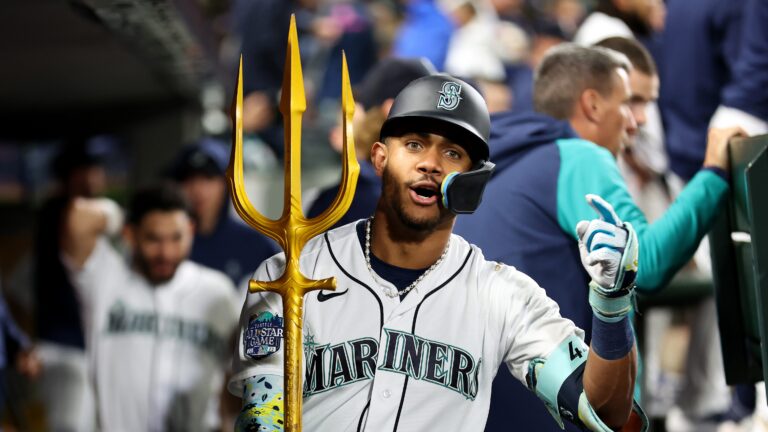 Julio Rodriguez of the Seattle Mariners celebrates his solo home run with the trident prop during the fourth inning against the Texas Rangers.