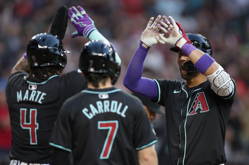 Lourdes Gurriel Jr. #12 of the Arizona Diamondbacks high fives Ketel Marte #4 and Corbin Carroll #7 after hitting a three-un home run against the St. Louis Cardinals during the MLB game at Chase Field.