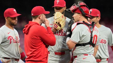 Cristopher Sánchez of the Philadelphia Phillies speaks with teammates at the pitcher's mound during the third inning of a baseball game against the Cincinnati Reds at Great American Ball Park.
