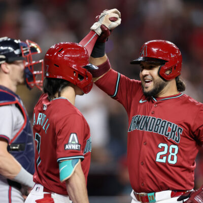 Eugenio Suárez of the Arizona Diamondbacks high fives Corbin Carroll #7 after hitting a solo home run against the Atlanta Braves during the fifth inning of the MLB game at Chase Field.
