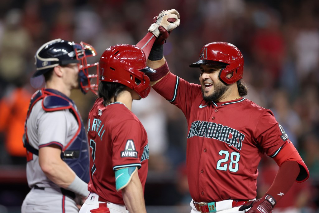 Eugenio Suárez of the Arizona Diamondbacks high fives Corbin Carroll #7 after hitting a solo home run against the Atlanta Braves during the fifth inning of the MLB game at Chase Field.