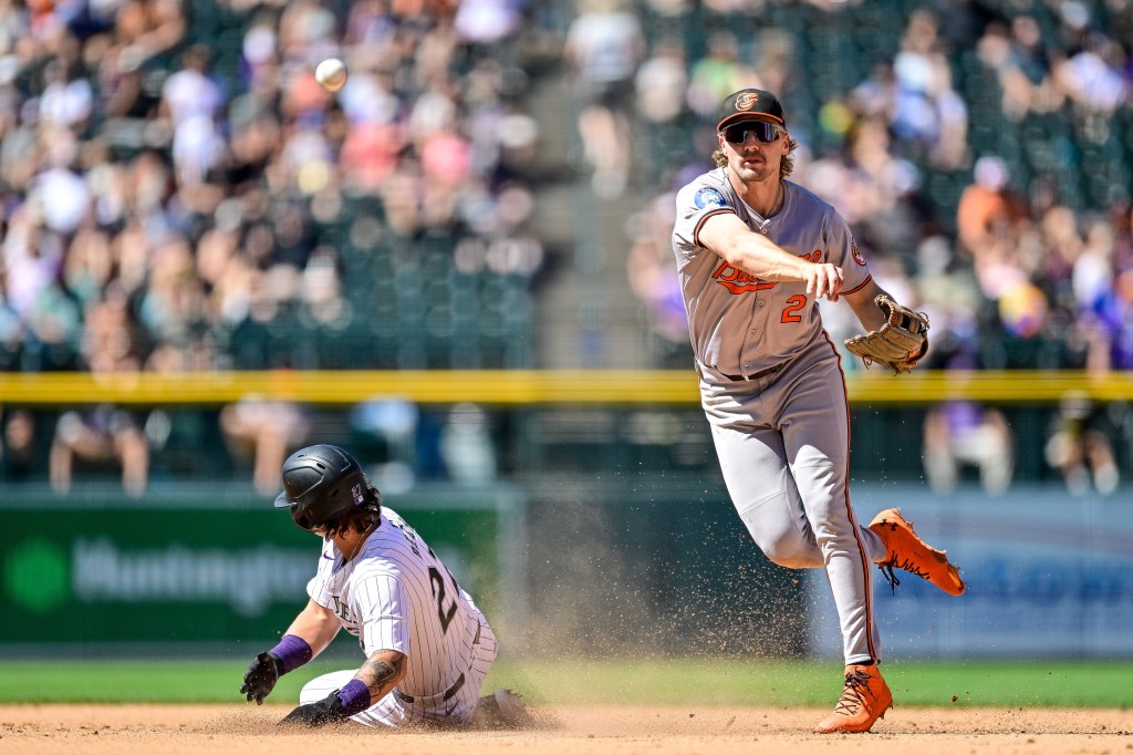 Gunnar Henderson #2 of the Baltimore Orioles throws to first to complete a sixth inning double play as Jordan Beck #27 of the Colorado Rockies slides at Coors Field.