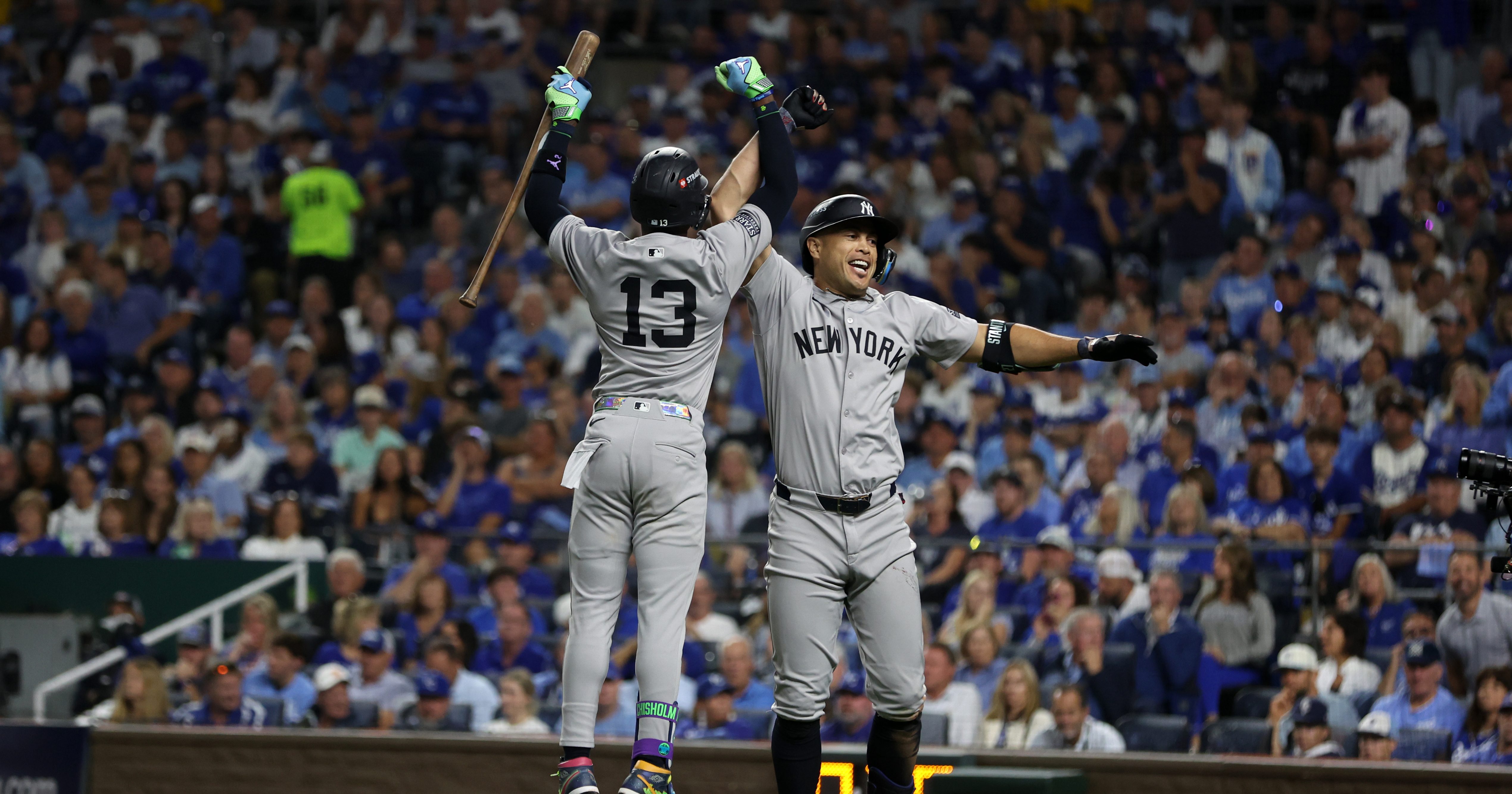 KANSAS CITY, MO - OCTOBER 9: Giancarlo Stanton #27 of the New York Yankees high fives Jazz Chisholm Jr. #13 after hitting a home run in the eighth inning of Game Three of the Division Series against the Kansas City Royals at Kauffman Stadium on October 9, 2024 in Kansas City, Missouri. (Photo by New York Yankees/Getty Images)