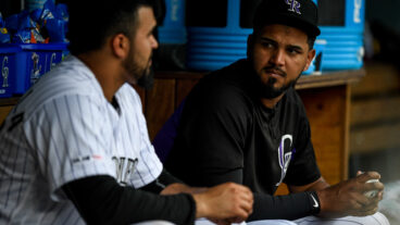 German Marquez #48 has a word with Antonio Senzatela #49 of the Colorado Rockies in the dugout during a game against the Cincinnati Reds.