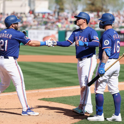 SURPRISE, ARIZONA - MARCH 02: Jake Burger #21 of the Texas Rangers high fives Joc Pederson #4 and Kevin Pillar #16 after hitting a two-run home run against the Arizona Diamondbacks during the fourth inning of the MLB game at Surprise Stadium on March 02, 2025 in Surprise, Arizona. (Photo by Christian Petersen/Getty Images)