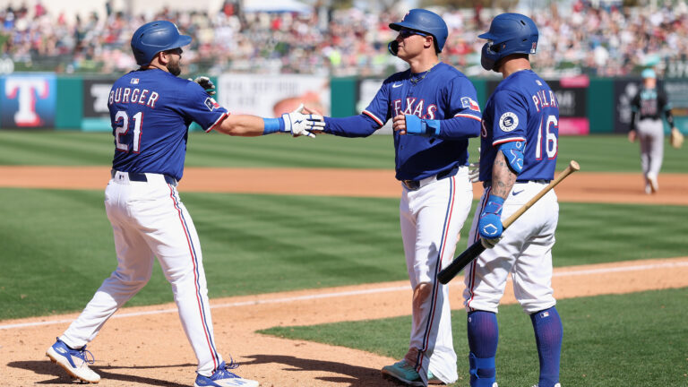 SURPRISE, ARIZONA - MARCH 02: Jake Burger #21 of the Texas Rangers high fives Joc Pederson #4 and Kevin Pillar #16 after hitting a two-run home run against the Arizona Diamondbacks during the fourth inning of the MLB game at Surprise Stadium on March 02, 2025 in Surprise, Arizona. (Photo by Christian Petersen/Getty Images)