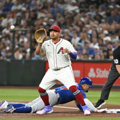 PHOENIX, ARIZONA - MARCH 27: Seiya Suzuki #27 of the Chicago Cubs slides safely into first base behind Josh Naylor #22 of the Arizona Diamondbacks in the second inning on Opening Day at Chase Field on March 27, 2025 in Phoenix, Arizona. (Photo by Norm Hall/Getty Images)