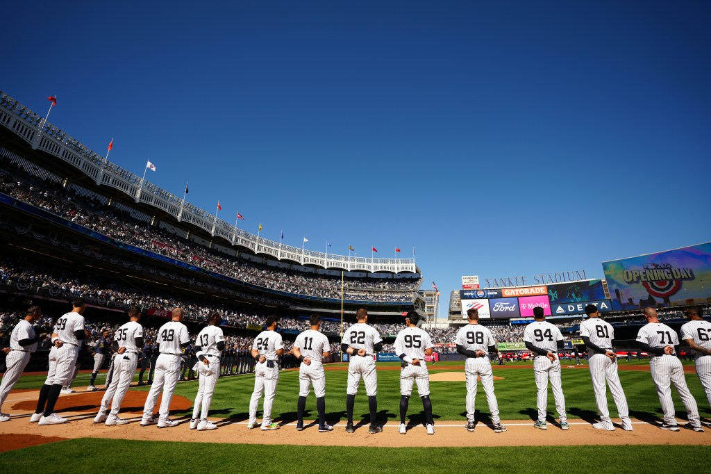 Members of the New York Yankees are seen on the base path during the singing of the national anthem prior to the game between the Milwaukee Brewers and the New York Yankees at Yankee Stadium.