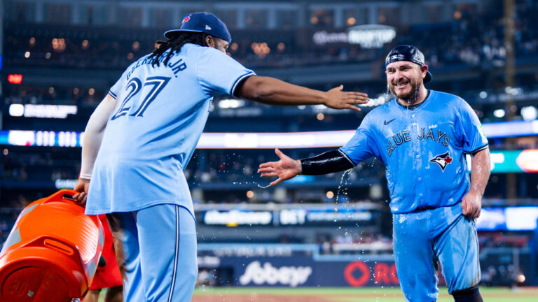 TORONTO, ON - APRIL 28: Alejandro Kirk #30 of the Toronto Blue Jays slap hands after getting doused in water by teammate Vladimir Guerrero Jr. #27 after their team defeated the Los Angeles Dodgers in their MLB game at the Rogers Centre on April 28, 2024 in Toronto, Ontario, Canada. (Photo by Mark Blinch/Getty Images)