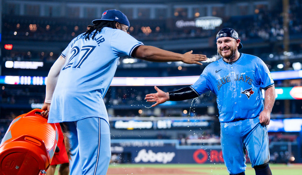 TORONTO, ON - APRIL 28: Alejandro Kirk #30 of the Toronto Blue Jays slap hands after getting doused in water by teammate Vladimir Guerrero Jr. #27 after their team defeated the Los Angeles Dodgers in their MLB game at the Rogers Centre on April 28, 2024 in Toronto, Ontario, Canada. (Photo by Mark Blinch/Getty Images)