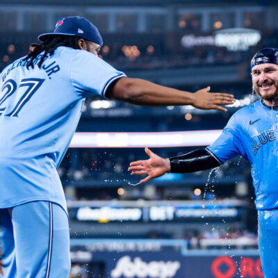 Alejandro Kirk #30 of the Toronto Blue Jays slap hands after getting doused in water by teammate Vladimir Guerrero Jr. #27