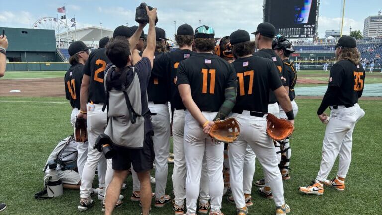 A group shot of the Tennessee Volunteers baseball team huddled up on the field.