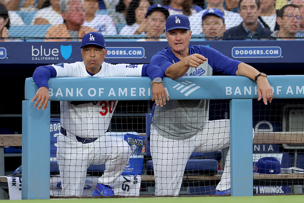 LOS ANGELES, CALIFORNIA - AUGUST 12: Manager Dave Roberts #30 and Bob Geren #88 of the Los Angeles Dodgers talk in the dugout during the first inning against the Kansas City Royals at Dodger Stadium on August 12, 2026 in Los Angeles, California. (Photo by Katelyn Mulcahy/Getty Images)